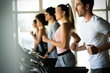 © NDABCREATIVITY - Group of young people running on treadmills in modern sport gym