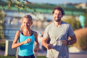 Modern woman and man jogging / exercising in urban surroundings near the river.