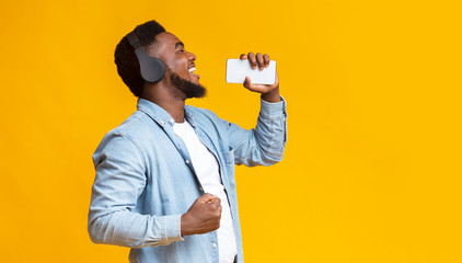 Poster - Cheerful african american man singing into smartphone like microphone