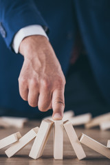 partial view of risk manager stopping domino effect of falling wooden blocks