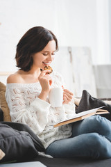 Wall Mural - happy girl reading book on sofa with coffee and cookies