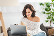 © LIGHTFIELD STUDIOS - attractive cheerful girl using laptop on sofa in cozy living room