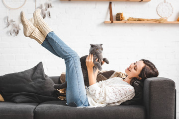 Wall Mural - beautiful cheerful girl lying on sofa with scottish fold cat