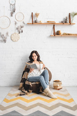 Wall Mural - brunette girl reading book in cozy living room with coffee and cookies