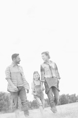 Young Caucasian family walking across field with young girl holding bouquet of flowers, concept organic ecologically friendly family