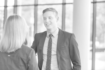 Wall Mural - Black and white photo of Young businessman talking with businesswoman in office during meeting