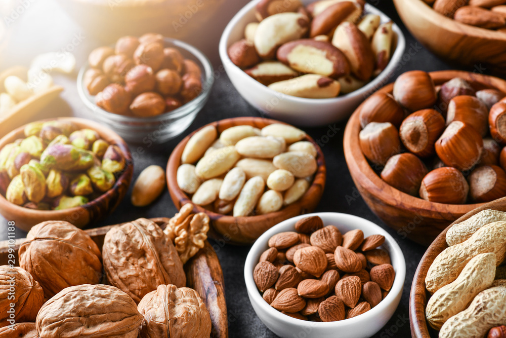 Mixed nuts in wooden bowls on black stone table. Almonds, pistachio, walnuts, cashew, hazelnut. Top view nut photo. - obrazy, fototapety, plakaty 