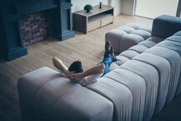 Brunette guy lying on cosy divan resting spending free spare time day daydream at open space work place station industrial brick loft interior house home