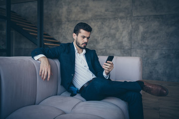 Sticker - Portrait of his he nice good-looking imposing attractive luxury focused bearded guy wearing jacket sitting on divan using digital device in industrial interior room indoors