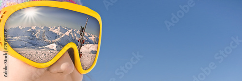 Fotografía Close up of a girl with a ski mask reflecting a snowy mountain and ski slope, bl