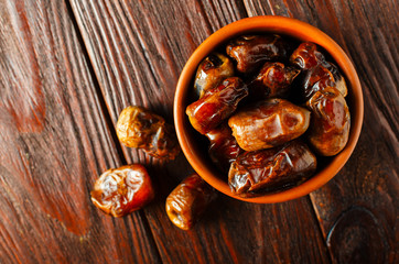 Clay brown bowl with dried dates on a wooden table. Healthy sweets, healthy nutrition. Traditional dessert in ramadan.