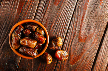 Clay brown bowl with dried dates on a wooden table. Healthy sweets, healthy nutrition. Traditional dessert in ramadan.