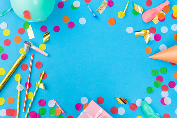 Wall Mural - celebration and decoration concept - pink birthday gift, party props, balloons and colorful confetti on blue background