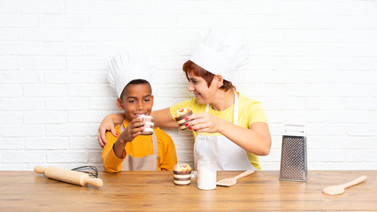 Wall Mural - Mother and her son dressed as chef in a kitchen