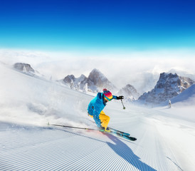 Wall Mural - Young man skier running down the slope in Alpine mountains