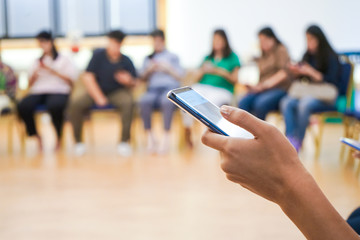 Electronic device on Asian Hand play social media in the meeting room with blur people behind