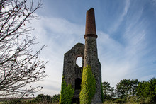An Abandoned Tin Mine Engine House And Chimney Against The Blue Autumn Sky
