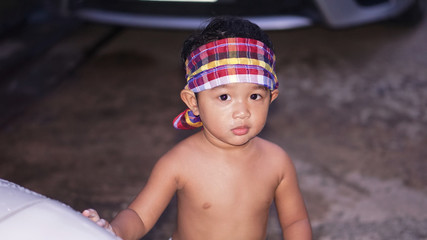 Happy Asian little boy 2 year old playing water from hose and spray to washing the car at outdoor in morning time. Kid and family activity concept.