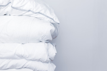 pile of white bedding items, pillows and a blanket on white background with copy space