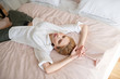 © zinkevych - Blonde woman wearing white shirt lying on bed