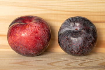 Group of two whole fresh red plum on natural wood