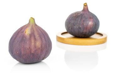 Group of two whole fresh purple fig on bamboo coaster isolated on white background