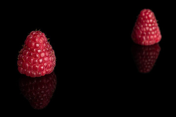 Group of two whole fresh red raspberry isolated on black glass