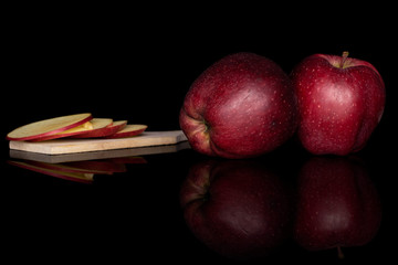 Wall Mural - Group of two whole four slices of fresh apple red delicious on wooden cutting board isolated on black glass