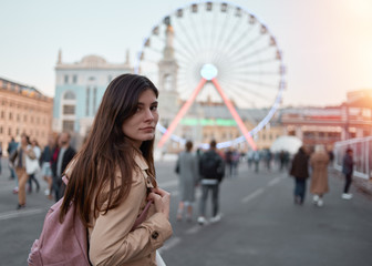 young woman in the city looking in camera. Beautiful Ferris wheel at the background.