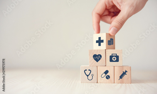 Cuadros en Lienzo Health Insurance Concept, Hand arranging wood cube stacking with icon healthcare medical on wood background, copy space, financial concept