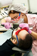 © Natalya Lys - Dentist young woman treats a patient a man. The doctor uses disposable gloves, a mask and a hat. The dentist works in the patient's mouth, uses a professional tool