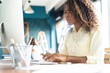 © opolja - Young african american businesswoman sitting in the office and working on laptop.