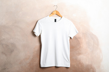 Wall Mural - Hanger with blank white t-shirt on brown background, space for text