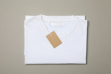 Wall Mural - Folded blank white t-shirt with tag on gray background, space for text