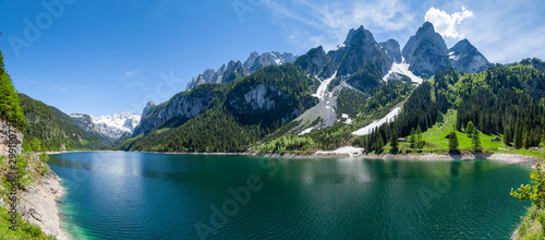 famous-lake-gosau-and-gosaukamm-with-mount-dachstein-spring-is-here-the-snow-is-melting-and-spring-brings-the-luscious-green-back-to-nature-the-sun-is-about-to-hide-behind-the-high-peaks