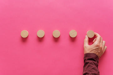 Wall Mural - male hand placing five wooden cut circles in a row