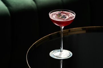 Wall Mural - Classic cocktail glass on glass table in night club restaurant, close-up