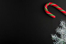 Traditional Christmas Caramel Candy Cane And Snowflakes On A Black Background. Winter Holiday Festive Greeting Card With Copy Space For The Text. Xmas Flat Lay Concept.