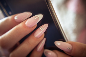 Women's hands with manicured nails holds smartphone