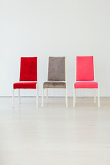 three multicolored chairs in the interior of an empty white room