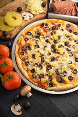 Italian pizza with ingredients on a dark background. Vertical photo.