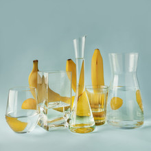 Still Life With Bananas And Lemons Through Glass Glasses, Wine Glasses, Vases Filled With Water.