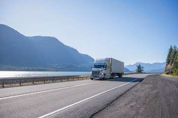 Big rig professional popular semi truck tor long haul freight transporting cargo in refrigerator semi trailer running on the road along the Columbia River at sunny day