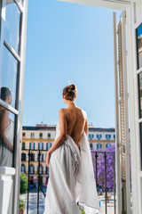 girl standing with her back to the camera at the open window