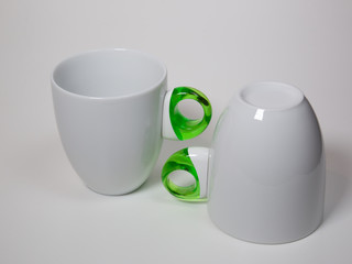 two white coffee cups with green handles isolated on a white background