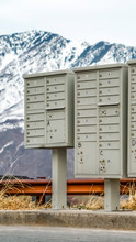Vertical Frame Mailboxes With Compartments And Numbers Against Snowy Mountain And Cloudy Sky