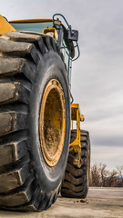 Wall Mural - Vertical Focus on the black rubber tires of a yelow bulldozer at a construction site