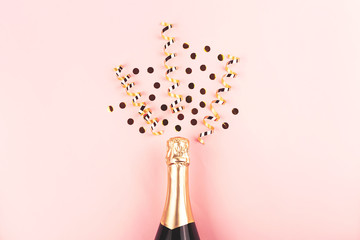 Creative New Year composition with champagne bottle and exploding gold confetti and streamers. Celebration and party concept.