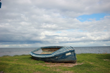 old wooden timber vintage unused fishing boat trawler pulled up retired on shore along the coast near fishing sheds along the seaside near Melbourne, Victoria, Australia