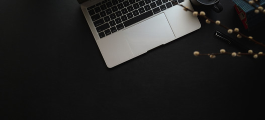 Overhead shot of dark modern workspace with laptop and office supplies on black leather desk